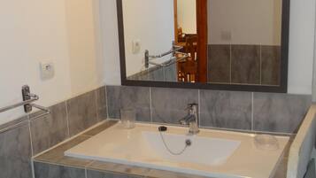 Une salle de bain dotée d’un grand miroir, de deux lavabos et d’un espace douche.