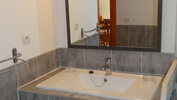 A bathroom with a large mirror, two sinks, and a shower area.