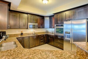 Eine moderne Küche mit Granit Arbeitsplatten, Edelstahlgeräten und dunklen Holzschränken.