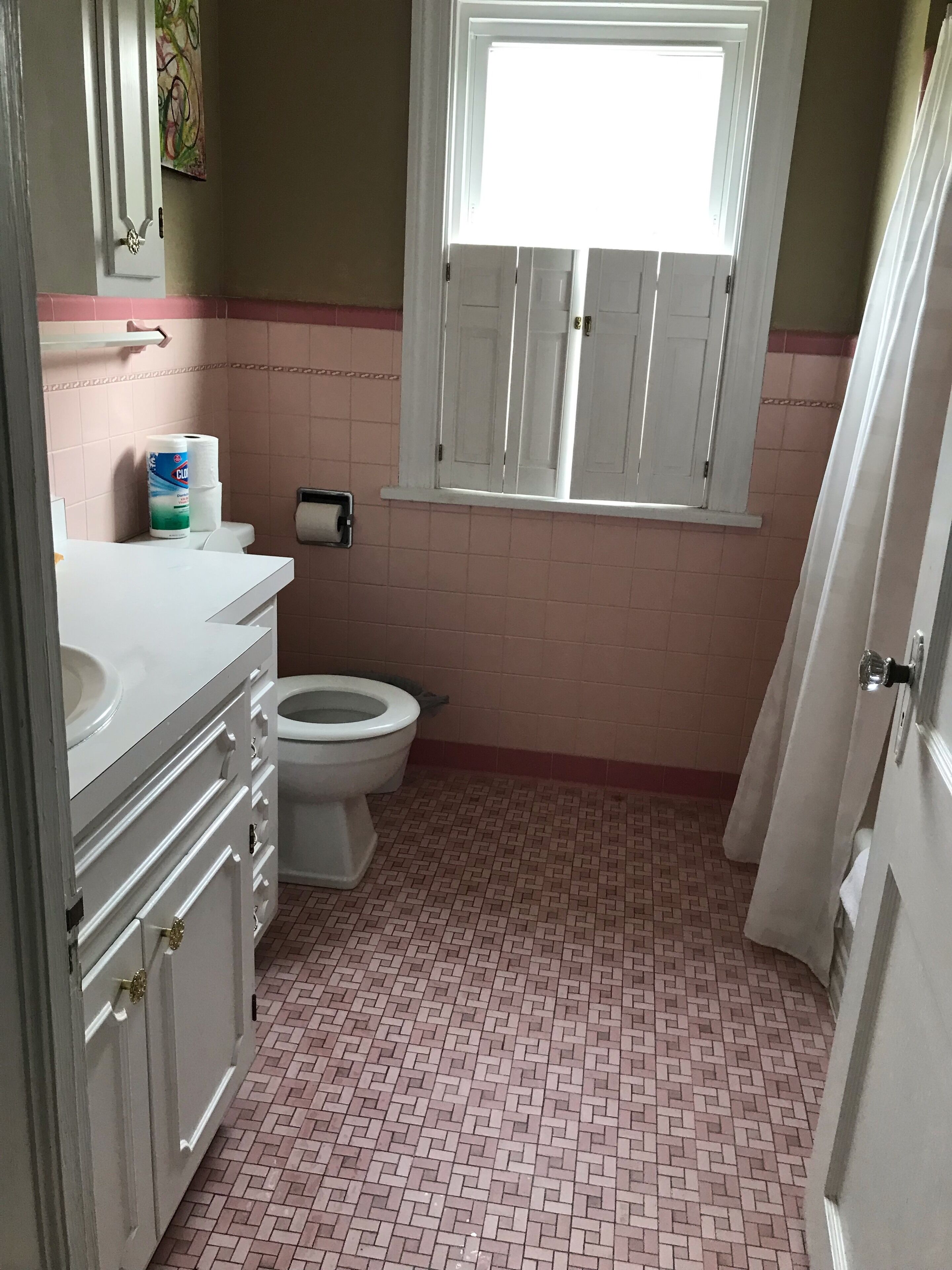 Une salle de bain avec des toilettes, un lavabo et une fenêtre située au-dessus des toilettes.