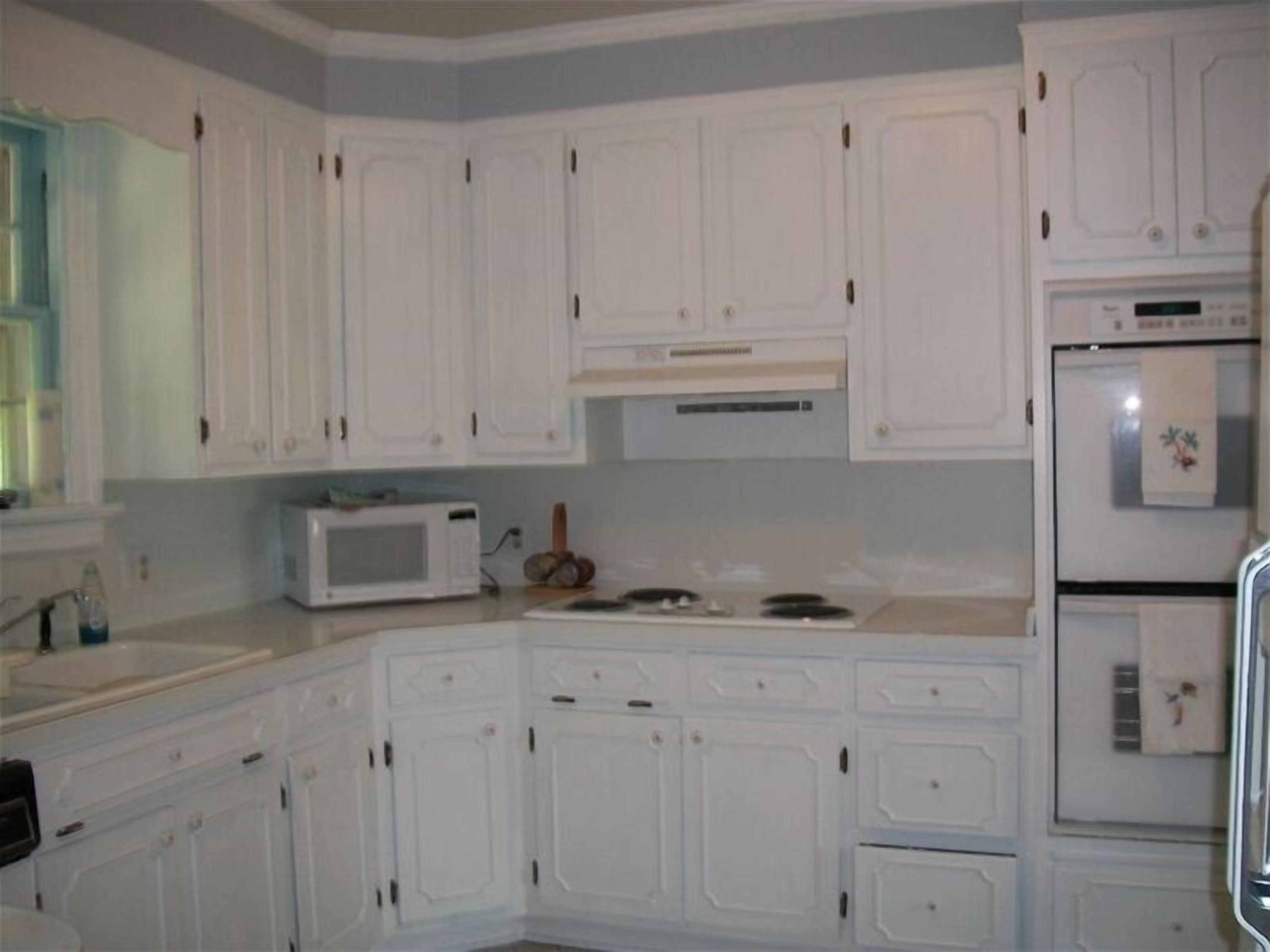 A kitchen with white cabinets, a microwave, a stove, and a refrigerator.