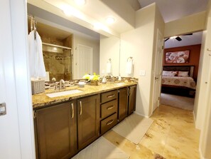 A modern bathroom with a large mirror, dual sinks, and a vanity with drawers.