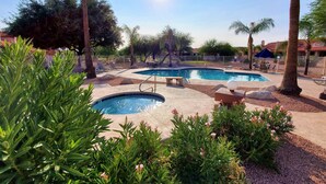 A pool area with multiple pools, lounge chairs, and palm trees.