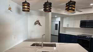 A modern kitchen with a large island, stainless steel appliances, and pendant lighting. - SPACIOUS OCEAN FRONT PARADISE (Fort Pierce)