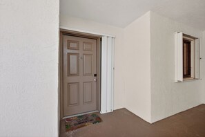 A hallway with a closed door and a window.