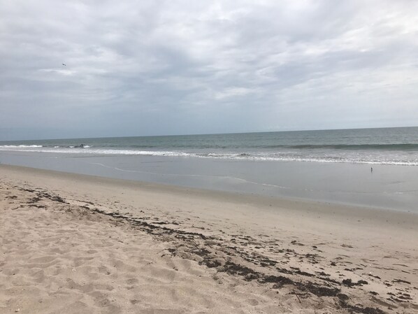 Une plage avec un rivage sablonneux et des vagues qui se rapprochent du rivage.
