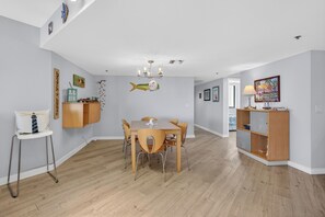 Un comedor con una mesa y sillas de madera, una araña y un mueble de pared.