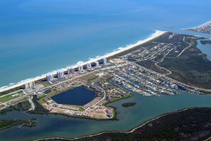 Vue aérienne d’une zone côtière comprenant un port de plaisance, une vaste étendue d’eau et une plage.