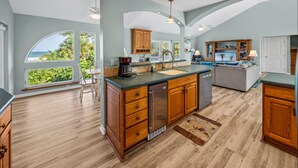 A spacious kitchen with a large island, wooden cabinets, and a view of the ocean.