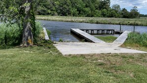 Un muelle de hormigón se adentra en un río tranquilo rodeado de abundante vegetación.