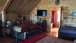 Un dormitorio rústico de cabaña con dos camas, un televisor y una cabeza de venado en la pared.