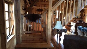 Un interior de madera con una escalera, una lámpara y una zona de bar.