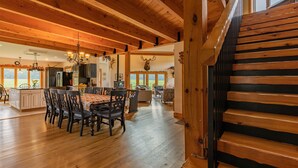 A spacious kitchen with wooden beams, a dining area with a table and chairs, and a staircase with wooden steps.