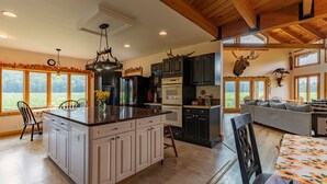 A spacious kitchen with a large island, dark cabinetry, and a rustic ceiling.