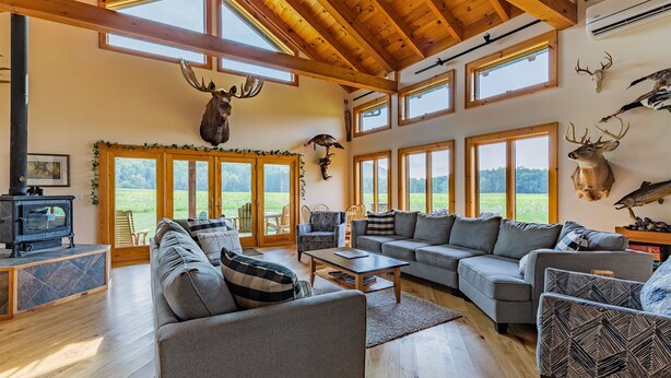 A spacious living room with a fireplace, large windows, and various animal skulls mounted on the walls.