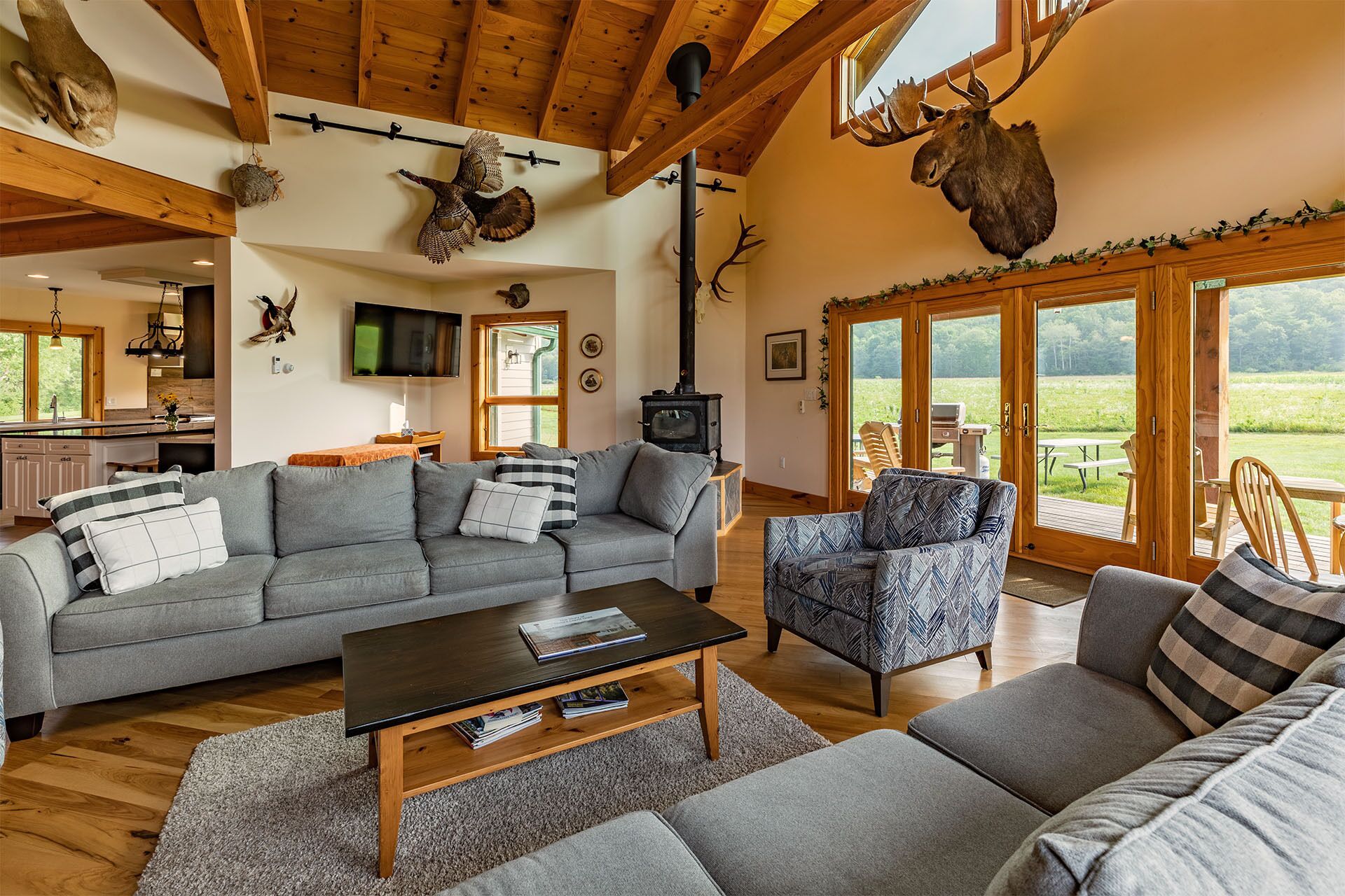 Un salón acogedor con chimenea, televisor y un ventanal con vistas a un paisaje verde.
