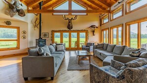 A spacious living room with a fireplace, large windows, and rustic decor including mounted animal heads.