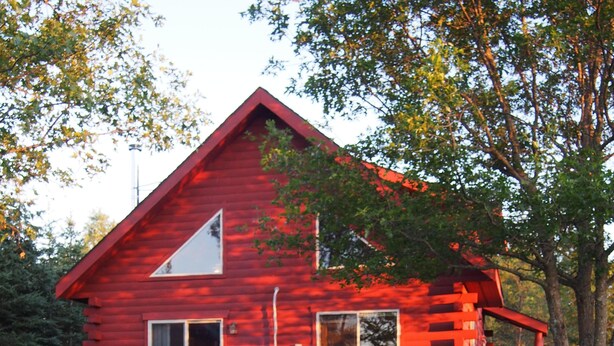 Una casa de madera roja con un brasero en la parte delantera.