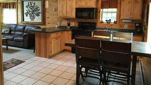 Una cocina acogedora de estilo rústico con armarios de madera, un microondas negro y un comedor con mesa y sillas.