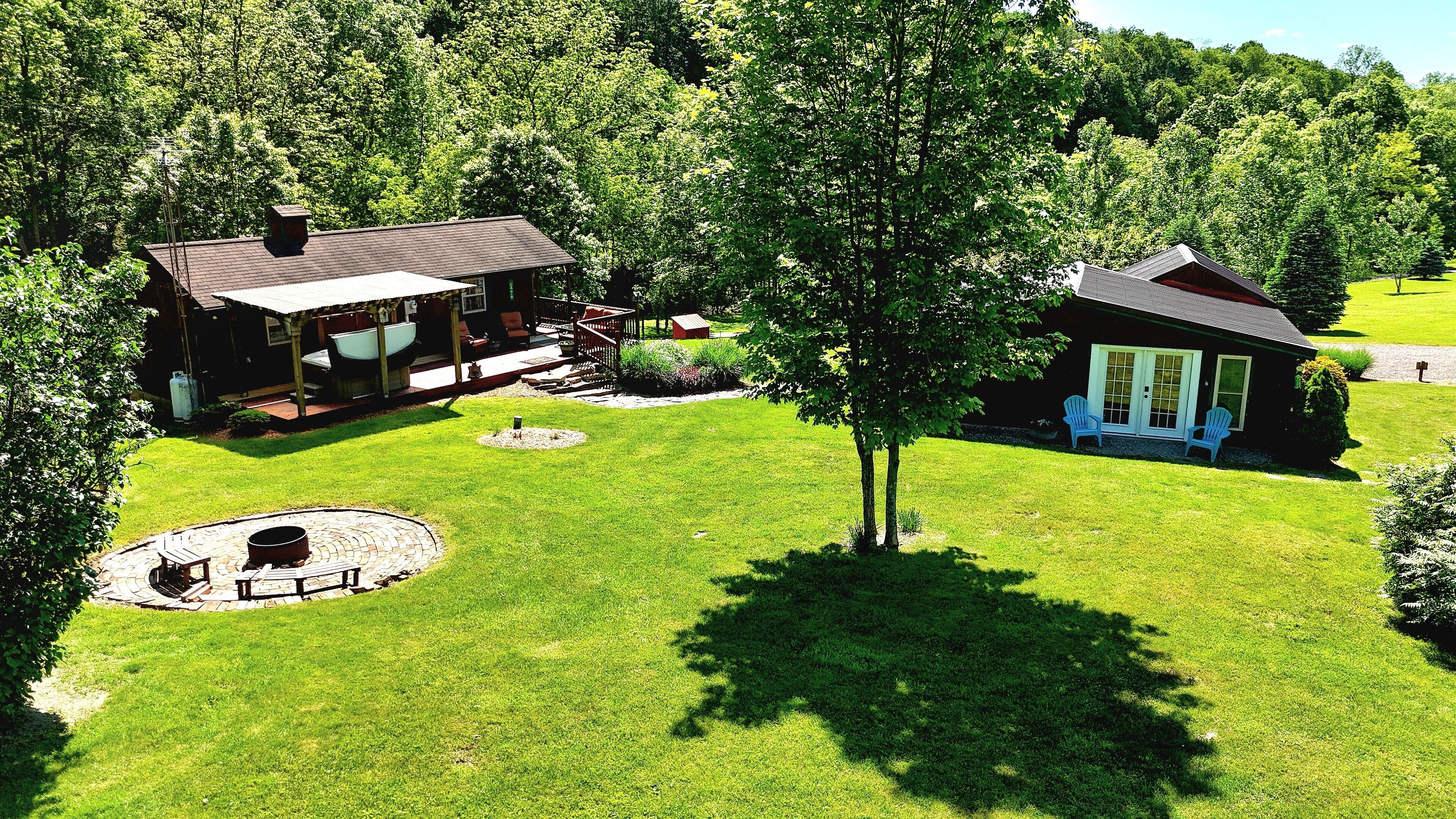Une grande maison avec un patio, un petit chalet et une pelouse bien entretenue.