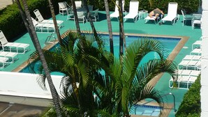 A pool area with multiple lounge chairs and umbrellas, surrounded by palm trees. - Cozy Top-Floor  Maui Parkshore Condo (Kihei)