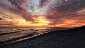 Ein Strand bei Sonnenuntergang mit Wellen, blauem Himmel und weiter Ferne.