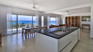 A spacious kitchen with a large island, modern appliances, and a view of the ocean. - Stunning Penthouse on Mullet Bay beach (Cupecoy)