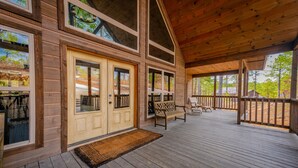 Eine Holzhütte mit Veranda, Doppeltüren und einer Bank.