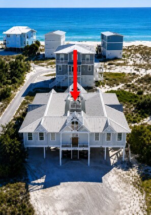 Une propriété située en bord de mer, comprenant un bâtiment principal, une route y menant et une plage en arrière-plan.