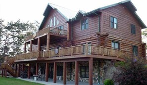 A large log cabin with a balcony and a covered porch.