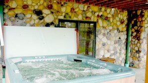 A hot tub with a stone wall backdrop. - Luxurious & Spacious!  A Great Place For Family, Friends, Reunions & Corporate! (Adams)
