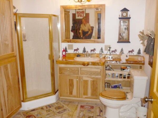 A bathroom with a wooden vanity, a toilet, and a mirror.