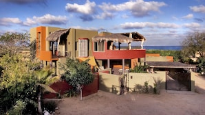 A modern house with a balcony overlooking a beach, surrounded by greenery. - Private 2 Bedroom Complex Close To Beach (Cabo Pulmo)