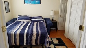 A bedroom with a bed, a nightstand, a lamp, and a door. -  Magnificent Gulf & Sunset Views in Belleair Beach (Belleair Beach)