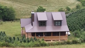 A house with a sloped roof, a wooden deck, and a large window.