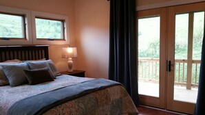 A bedroom with a bed, a nightstand with a lamp, a window, and a sliding glass door to a balcony.