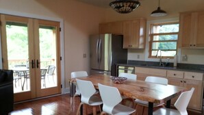A modern kitchen with wooden cabinets, a large dining table, and white chairs.