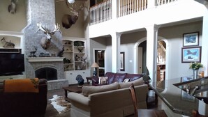 A spacious living room with a fireplace, a sofa, and a television. - Whitetail Ranch Manor Retreat (Bryan)