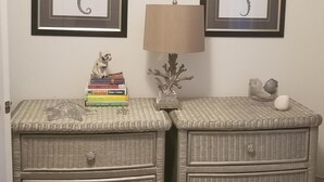 Une chambre à coucher avec deux tables de chevet, chacune ornée d’une œuvre d’art représentant un hippocampe encadré, d’une lampe et d’une pile de livres.
