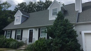 A two-story house with a grey roof, white siding, and a large evergreen tree in front. - Narraganett 4BR, Pier Neighborhood, Walk 2 Amenities, Dog-friendly, dead-end st. (Narragansett)