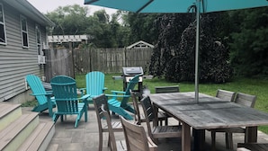 A patio with a wooden table and chairs, a grill, and a turquoise umbrella. - Narraganett 4BR, Pier Neighborhood, Walk 2 Amenities, Dog-friendly, dead-end st. (Narragansett)