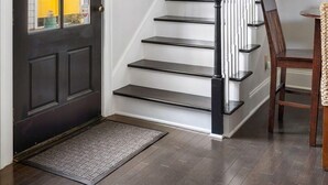 Un escalier avec des rampes noires et des marches blanches, menant à l’étage supérieur.