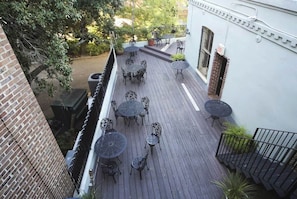 Terraza en la azotea con varias mesas y sillas redondas, rodeada de un muro de ladrillo y una barandilla metálica.