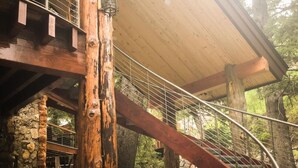 A wooden staircase with metal railings, a stone wall, and a wooden ceiling. - Refined creekside retreat • Barrel sauna overlooking the river • Hot tub • Starlight evenings • Minutes to Sundance (Sundance)