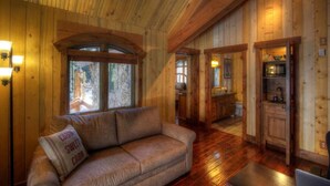 A wooden cabin interior with a sofa, wooden walls, and a kitchen area. - Refined creekside retreat • Barrel sauna overlooking the river • Hot tub • Starlight evenings • Minutes to Sundance (Sundance)