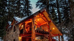 A log cabin with a wooden exterior, a balcony, and a staircase leading to the upper level. - Refined creekside retreat • Barrel sauna overlooking the river • Hot tub • Starlight evenings • Minutes to Sundance (Sundance)
