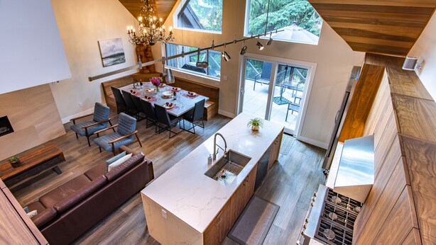 A modern kitchen with a central island, dining area with chairs, and a large window overlooking a deck. - Pinnacle Ridge 23 - Ski in Ski out, Private Hot Tub, Gas Fireplace (Whistler)