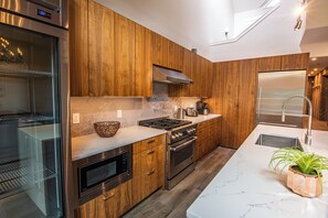 Una cocina moderna con armarios de madera, electrodomésticos de acero inoxidable y encimera de mármol.