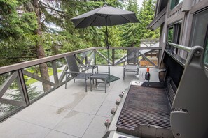 An outdoor patio with a grill, seating, and an umbrella. - Pinnacle Ridge 23 - Ski in Ski out, Private Hot Tub, Gas Fireplace (Whistler)
