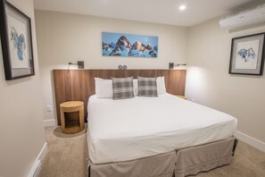 A neatly arranged bedroom with a large bed, a wooden headboard, and a painting of mountains on the wall. - Pinnacle Ridge 23 - Ski in Ski out, Private Hot Tub, Gas Fireplace (Whistler)